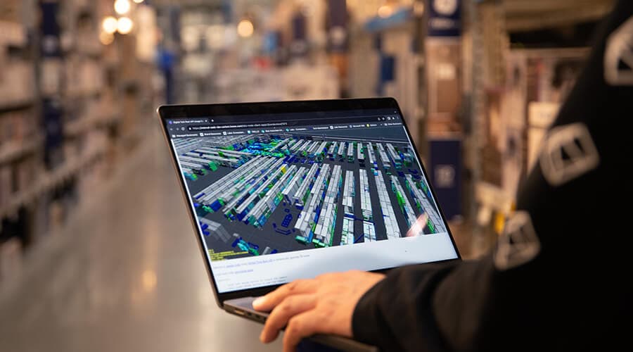 A laptop showing a live data view, held in a working stockroom.